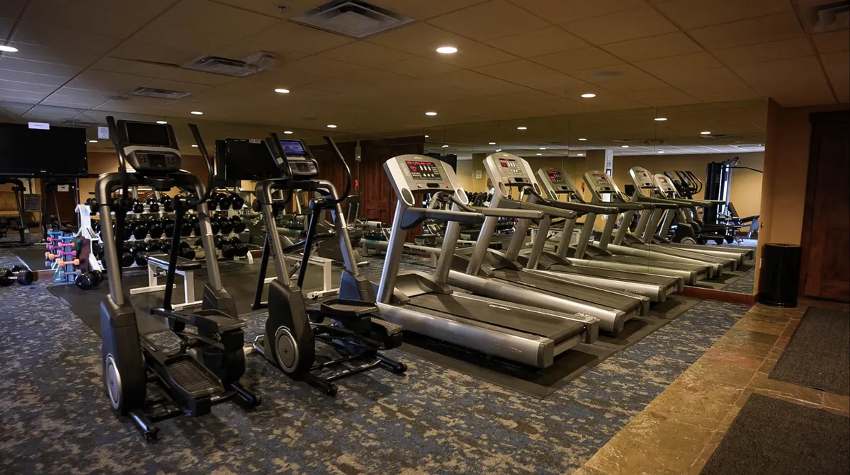 This interior image showcases a well-equipped fitness center featuring treadmills, ellipticals, dumbbells, and a mirrored wall. The space looks modern and motivational, inviting residents to stay active without leaving the building.