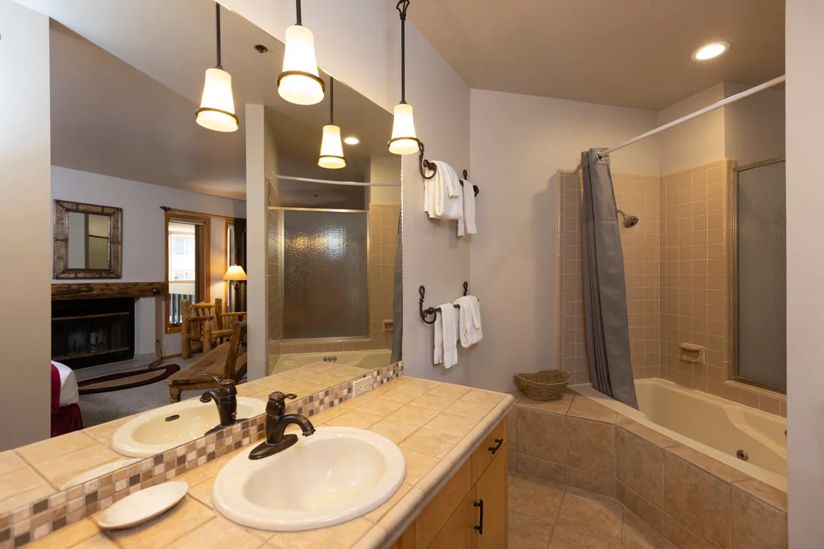 A spacious, modern bathroom featuring a double sink vanity with a large mirror, a deep soaking bathtub, and a separate shower area. The space is clean, bright, and designed for ultimate relaxation and self-care.